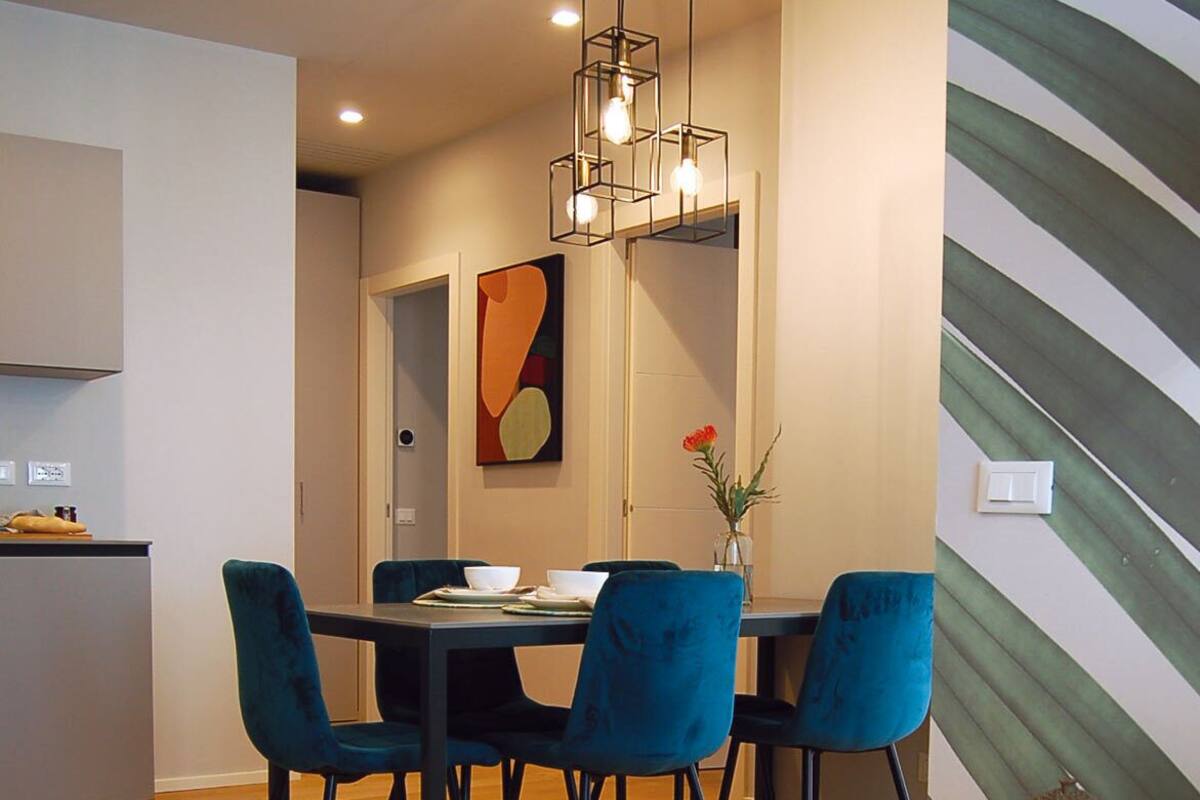 A modern dining area with a wooden table, blue chairs, and a hanging light fixture.