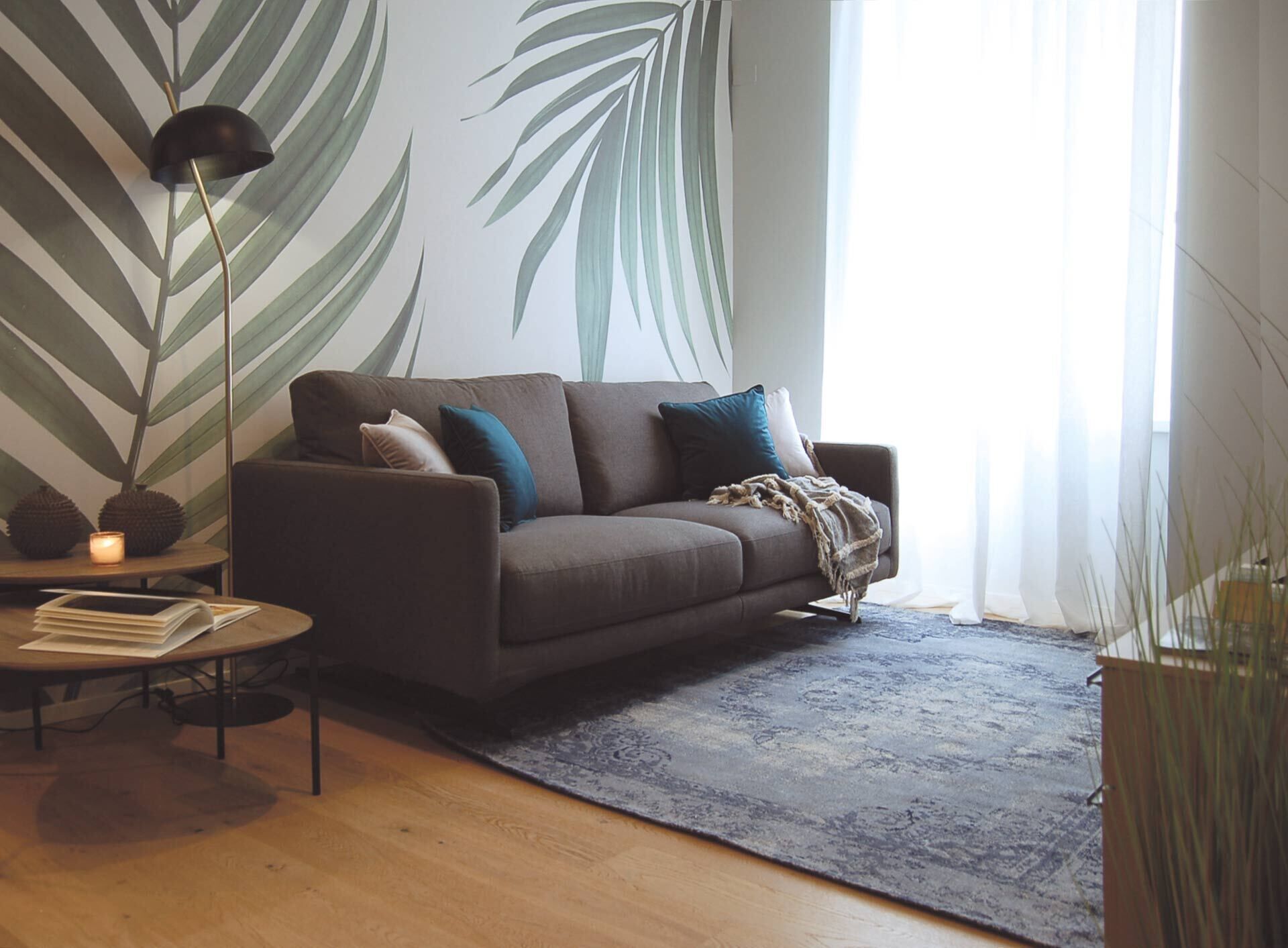 A modern living room with a sofa, a coffee table, a floor lamp, and a large wall mural.