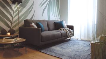 A modern living room with a sofa, a coffee table, a floor lamp, and a large wall mural.
