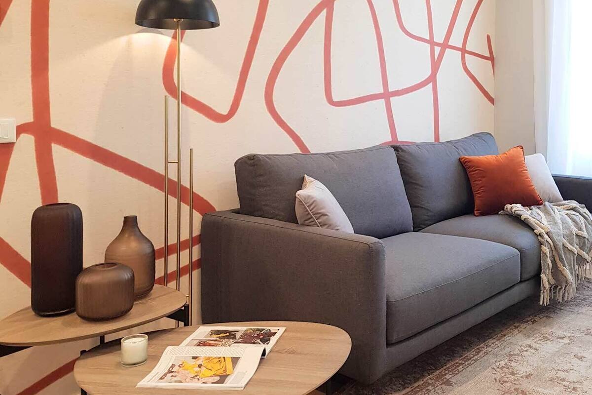 A modern living room with a grey sofa, a round coffee table, and a patterned rug.