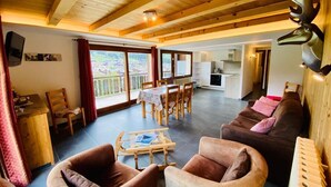 Un vaste espace de vie doté d’un plafond en bois, d’une table à manger et d’un canapé.