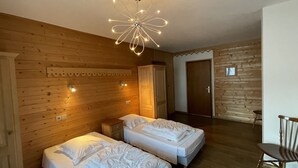 Une pièce avec deux lits, des murs en bois, un plafond en bois, un lustre et une porte.