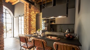 Une cuisine moderne dotée d’un îlot central, de tabourets de bar et d’un mur d’accent en pierre.
