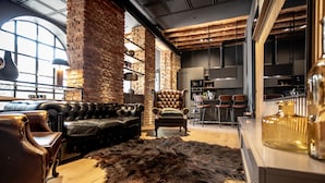 Un intérieur moderne avec des canapés en cuir, un tapis en fourrure et des murs en briques apparentes.