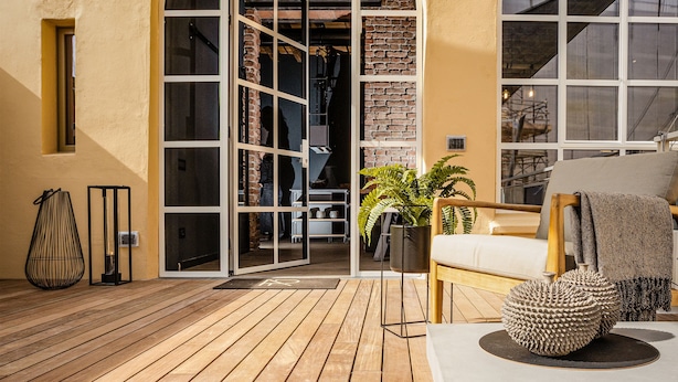 Une terrasse en bois avec un canapé blanc et une plante en pot.