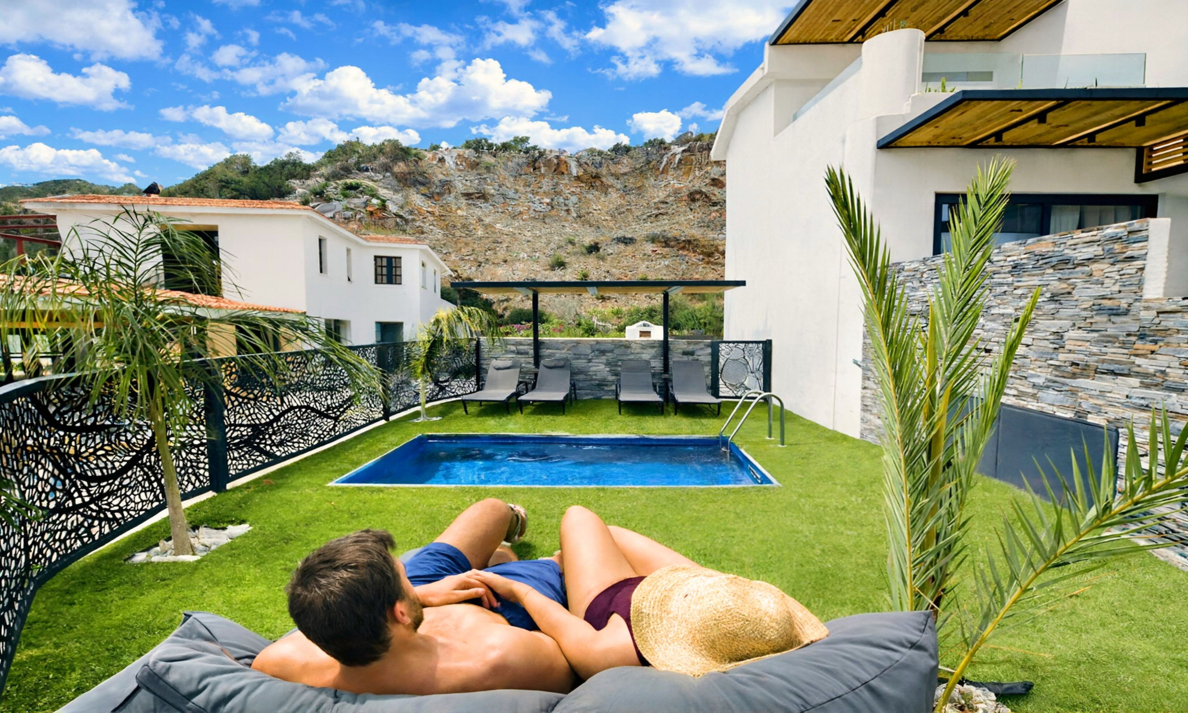 A couple relaxing by a pool with a view of a mountainous landscape.