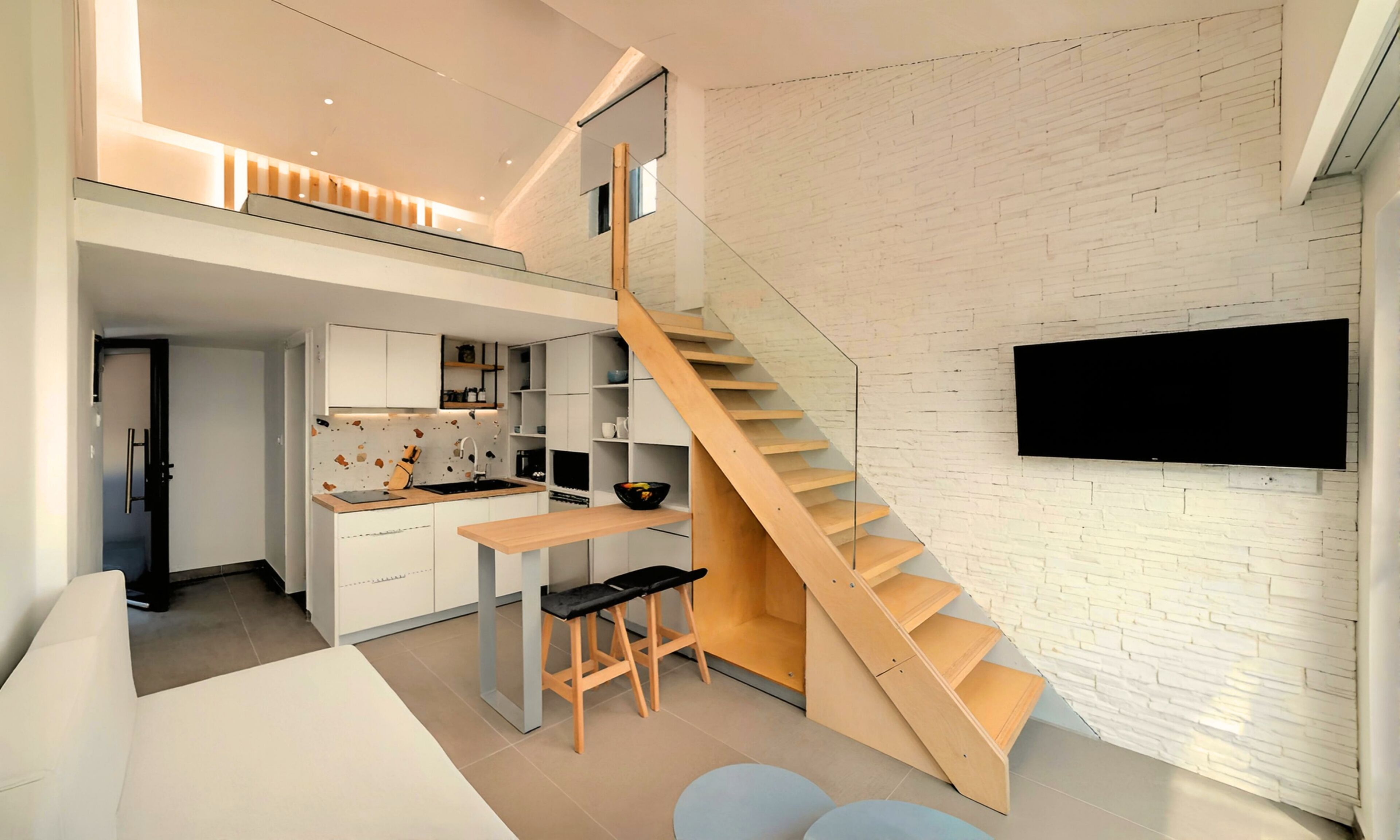 A modern kitchen with a wooden staircase, a dining area, and a TV mounted on the wall.