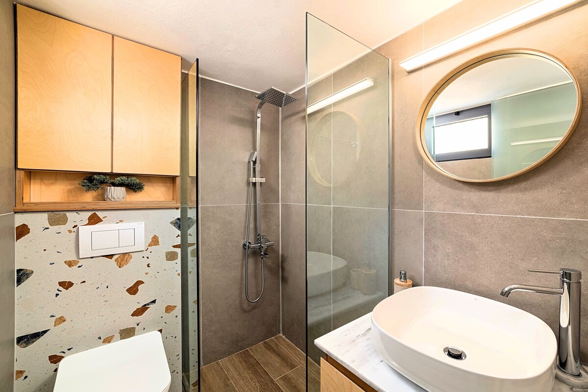 A modern bathroom with a shower, a sink, and a mirror.