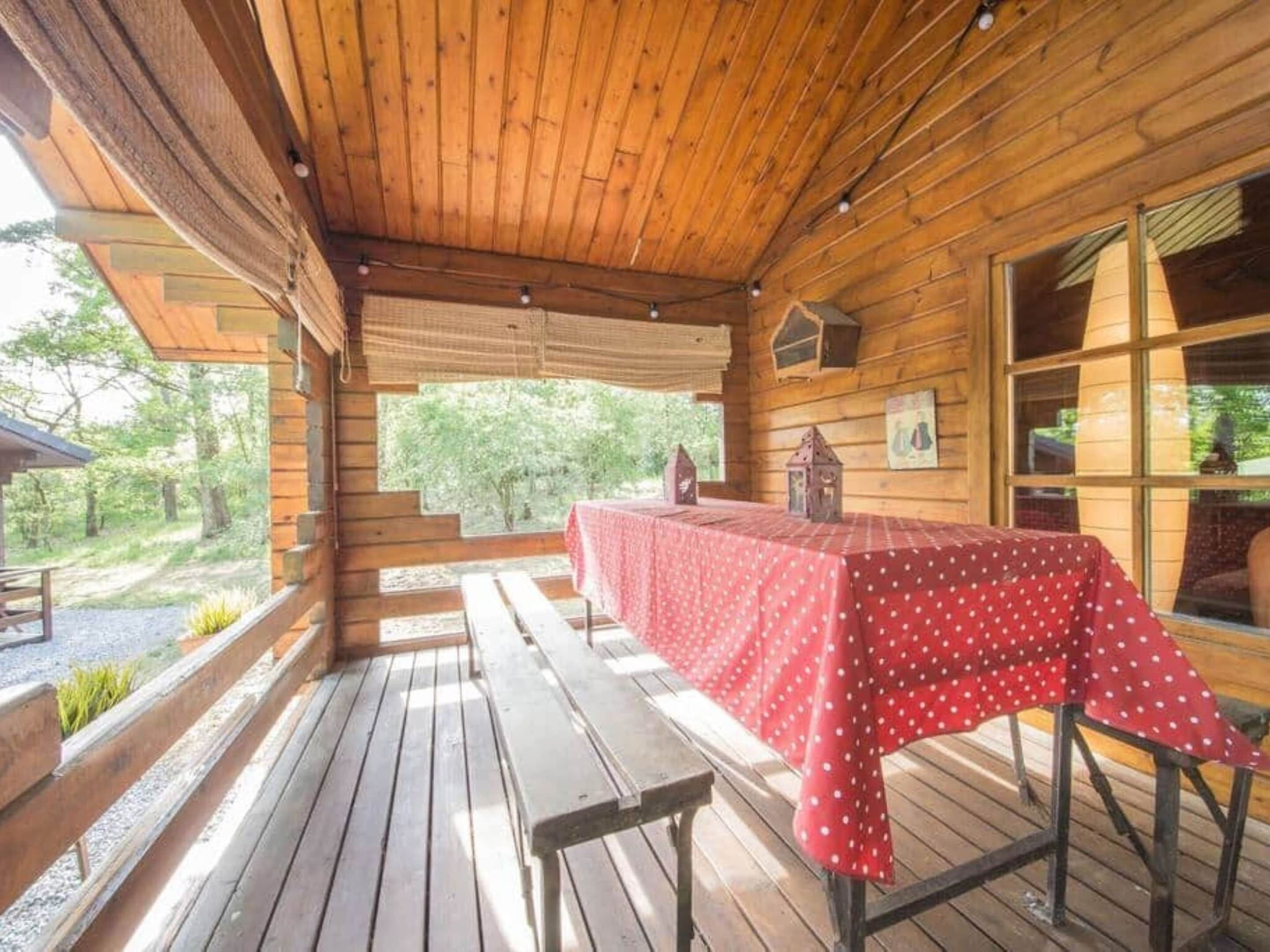 A wooden deck with a table covered in a red polka dot tablecloth.