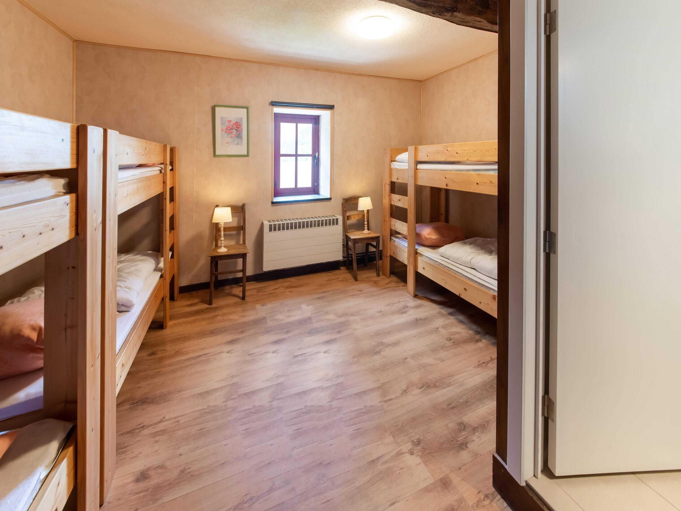 A room with two bunk beds, a window, a radiator, and a chair.