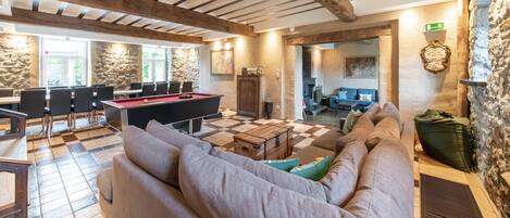 A cozy indoor space with a pool table, sofas, and a dining area with chairs.