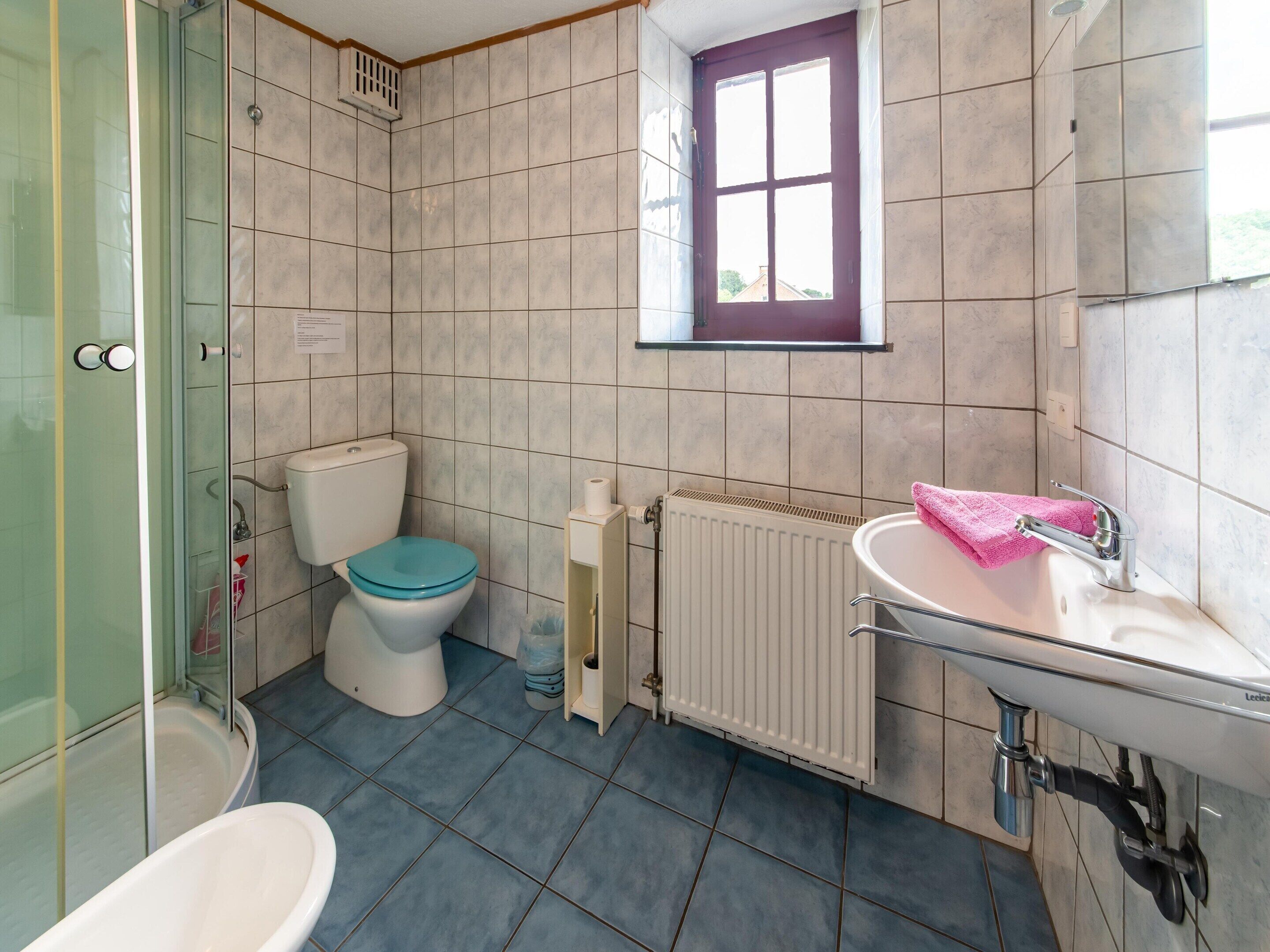 Une salle de bain avec des toilettes, une baignoire, un lavabo et une fenêtre.
