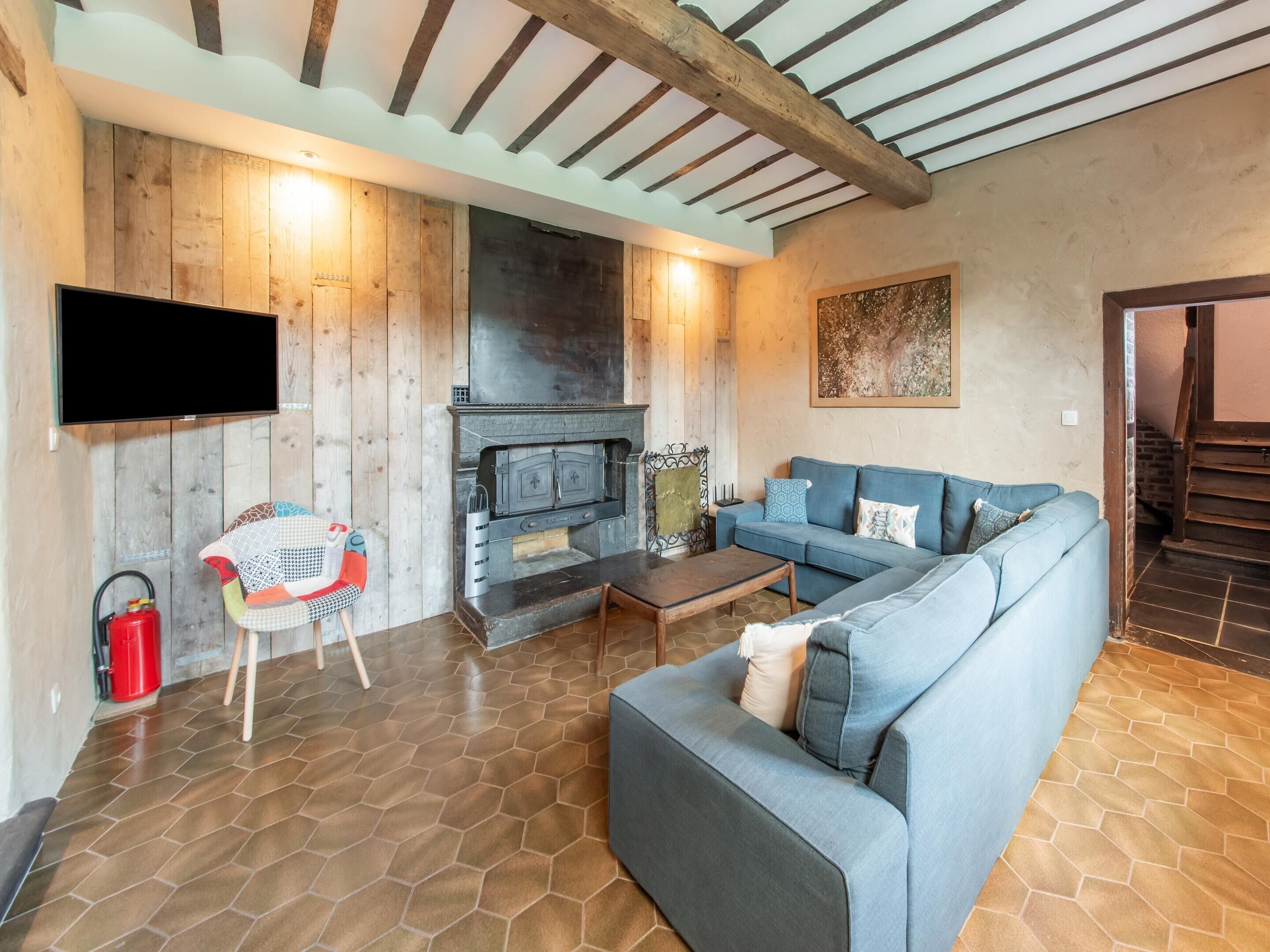 Una sala de estar con un sofá modular, una chimenea, un televisor y un techo de madera.