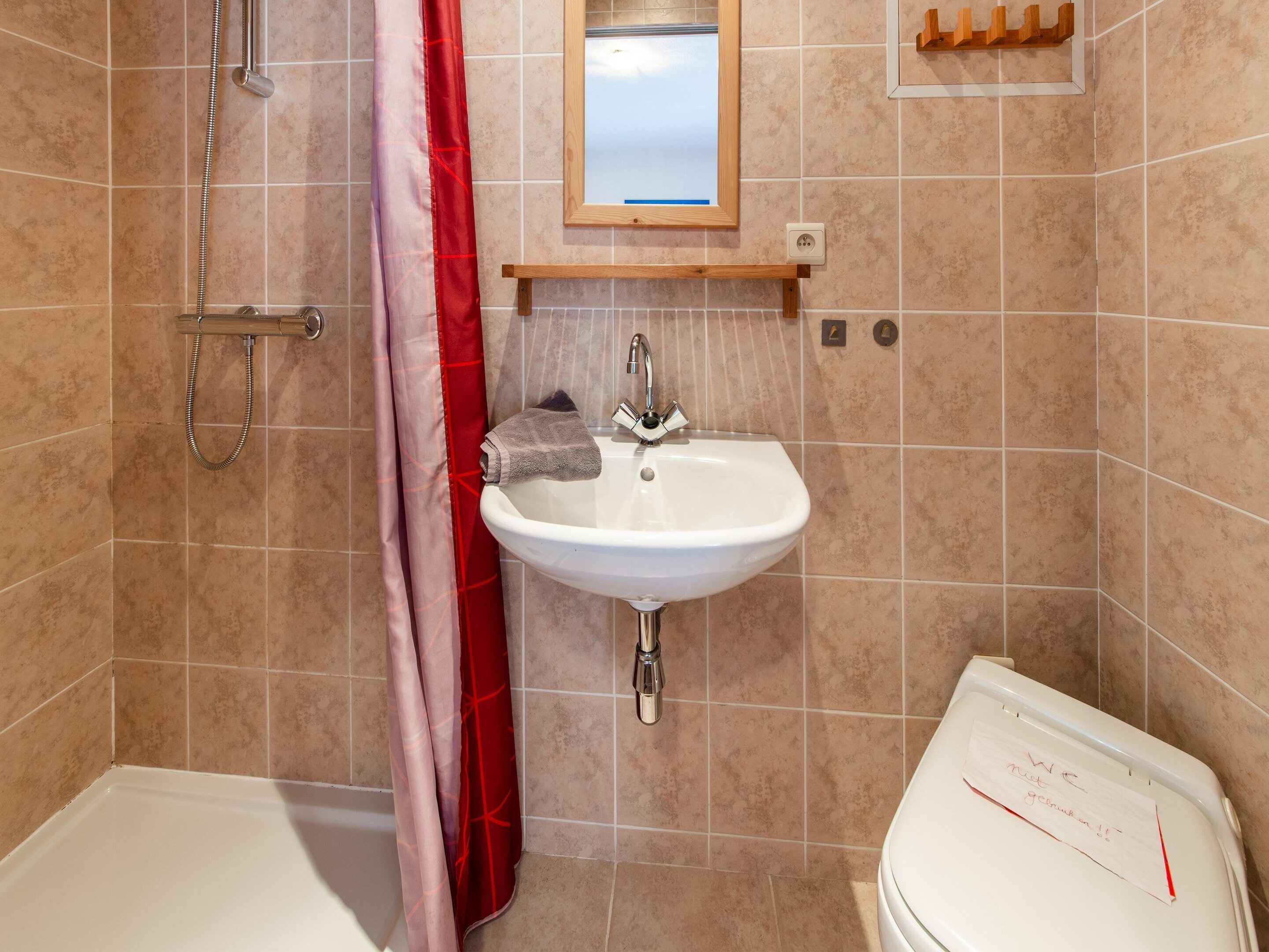 A bathroom with a white sink, a shower, and a toilet.