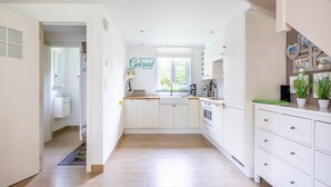 Une cuisine moderne avec des meubles blancs, un four encastré et une fenêtre qui laisse entrer la lumière naturelle.