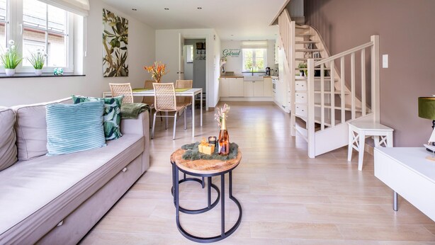 Un salon moderne avec un canapé, une table à manger et des chaises. Un escalier mène à un niveau supérieur.