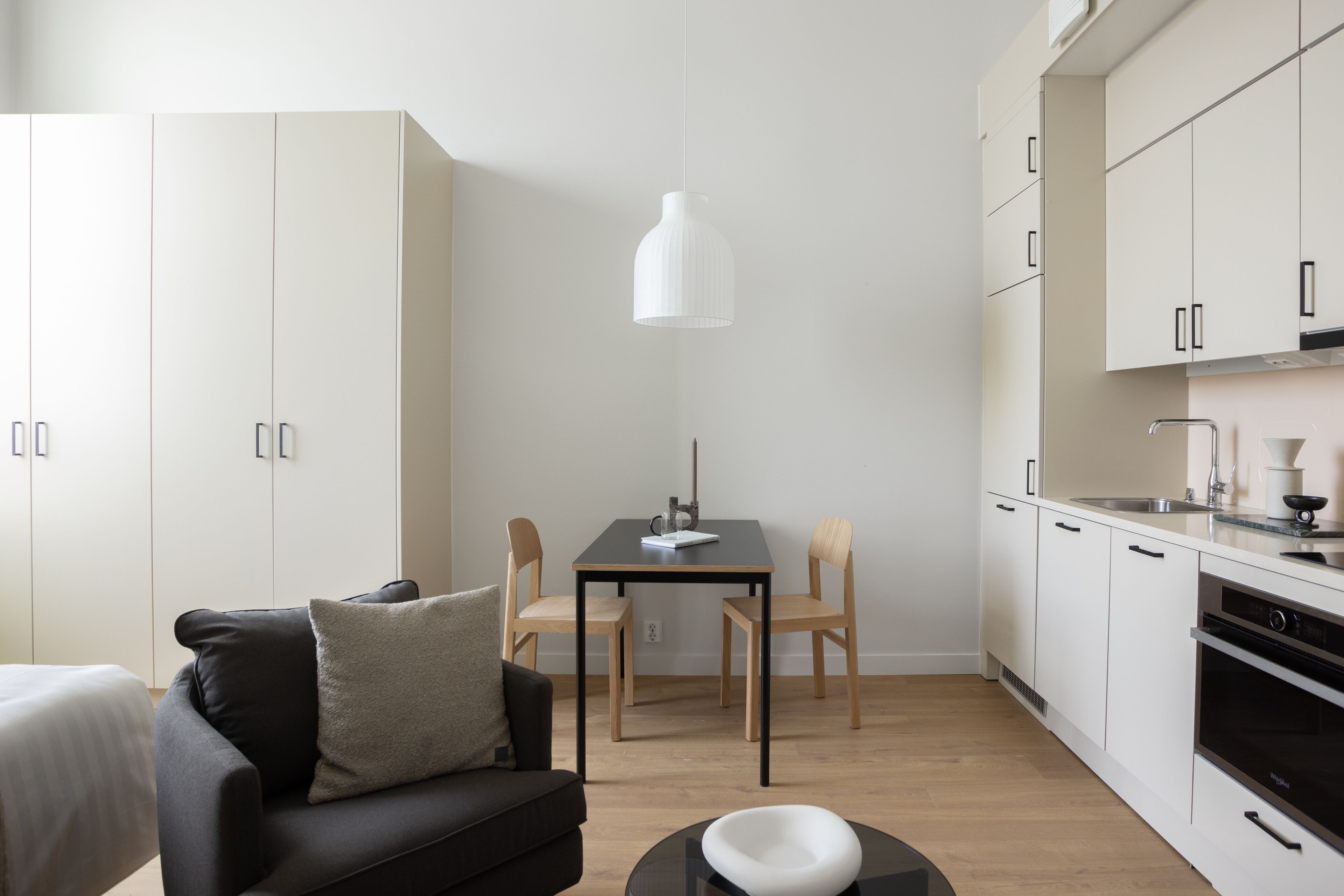 A modern kitchen with white cabinets, a black countertop, and a dining area with a table and chairs.