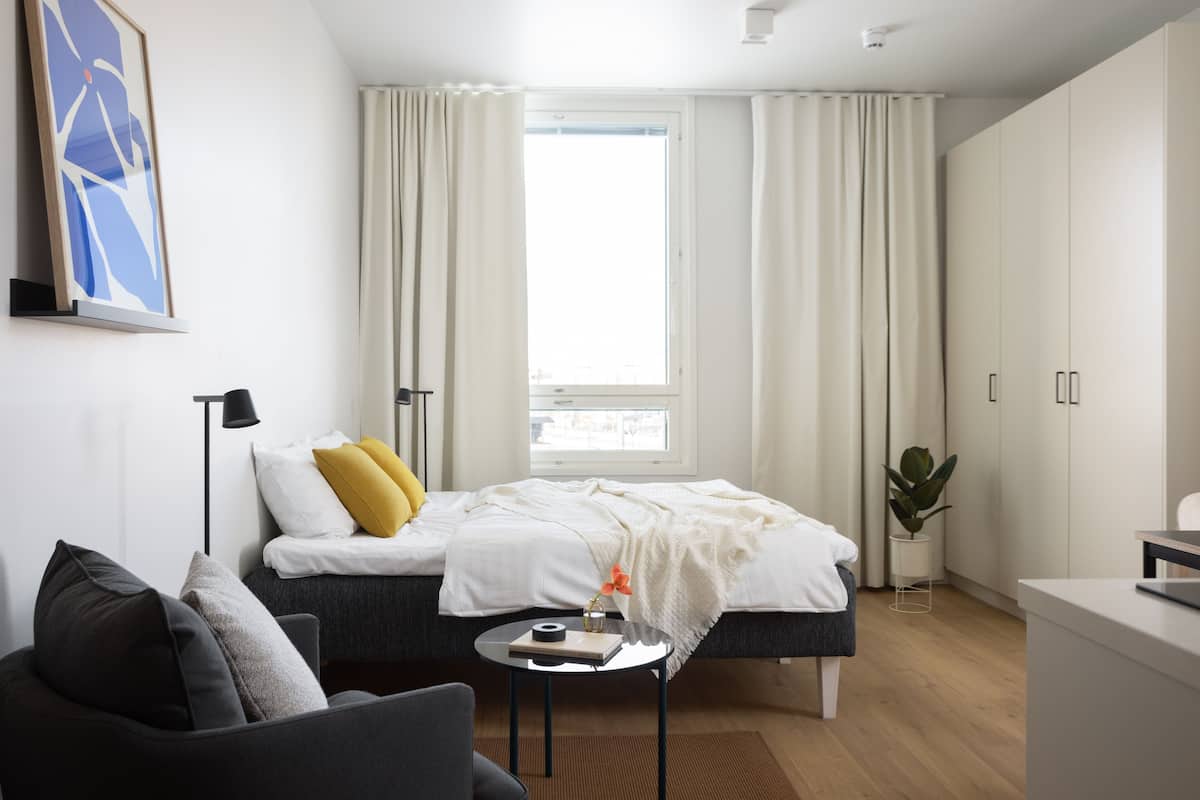 Quarto moderno com cama, mesa de cabeceira e escrivaninha.