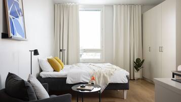 A modern bedroom with a bed, bedside table, and a desk.