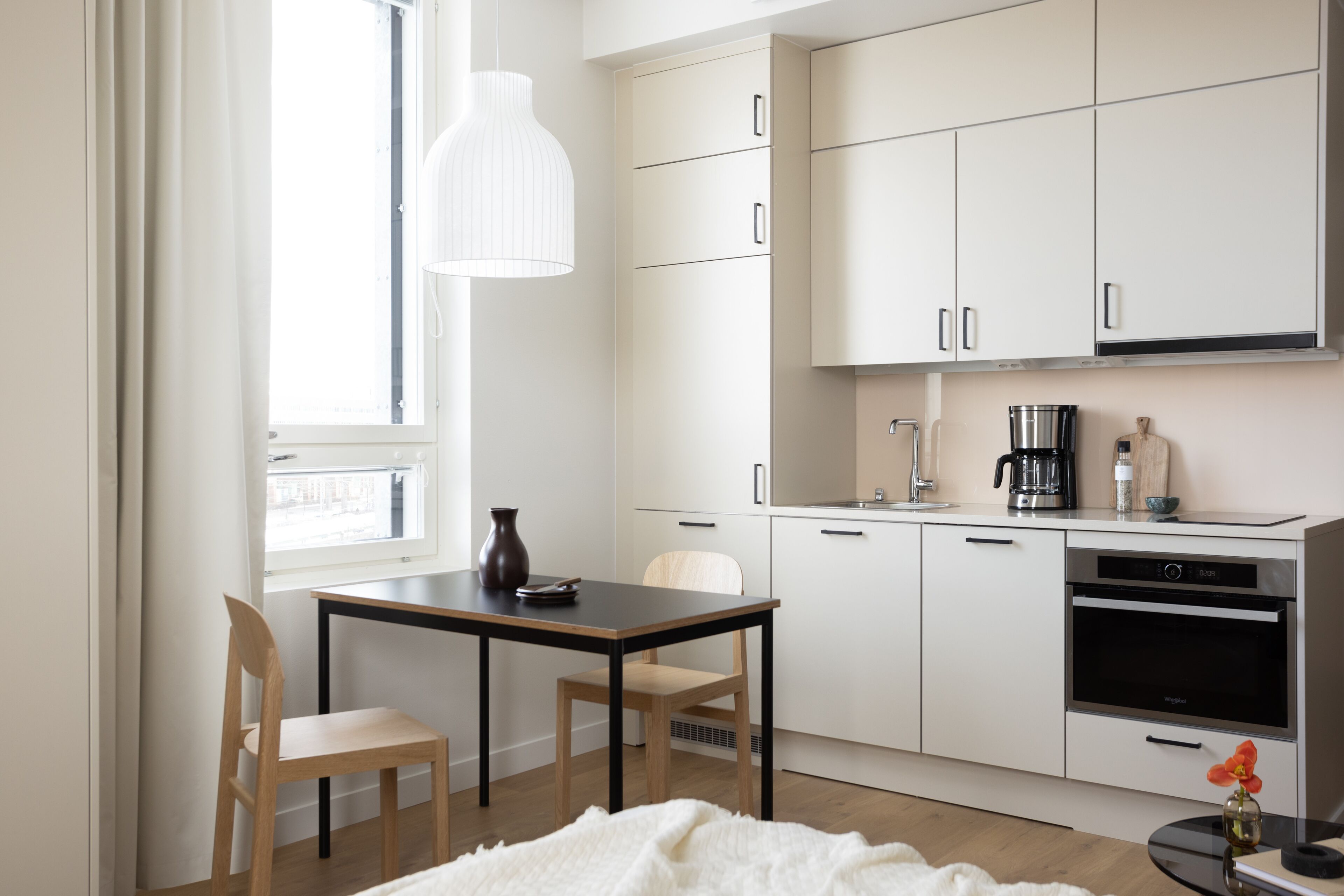 A modern kitchen with white cabinets, a coffee maker, and a built-in oven.
