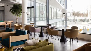 A modern lounge area with comfortable seating, a pool table, and large windows offering views of the city. - Noli Malmi (Helsinki)