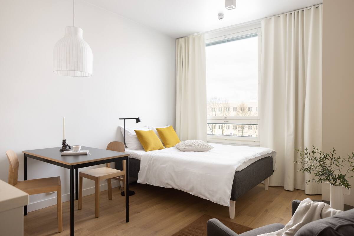 Quarto de hotel moderno com cama, escrivaninha e área de refeições.