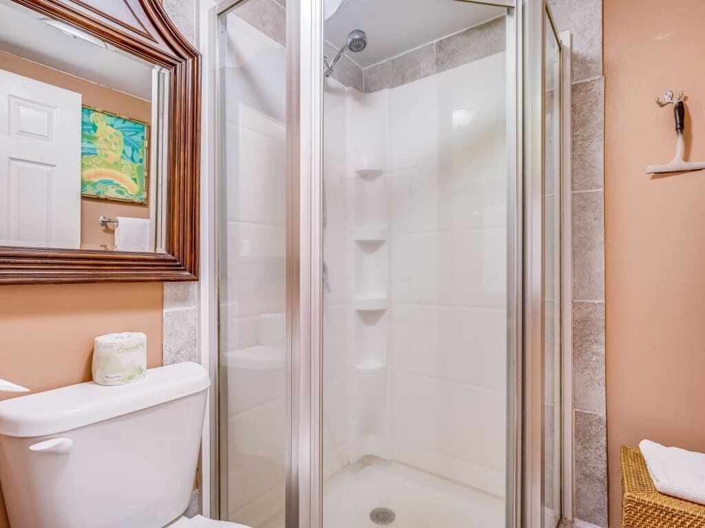 Une salle de bain avec une douche à parois de verre, des toilettes et un lavabo.