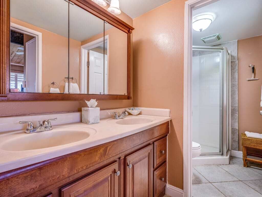 A bathroom with a double sink vanity, a large mirror, and a walk-in shower.