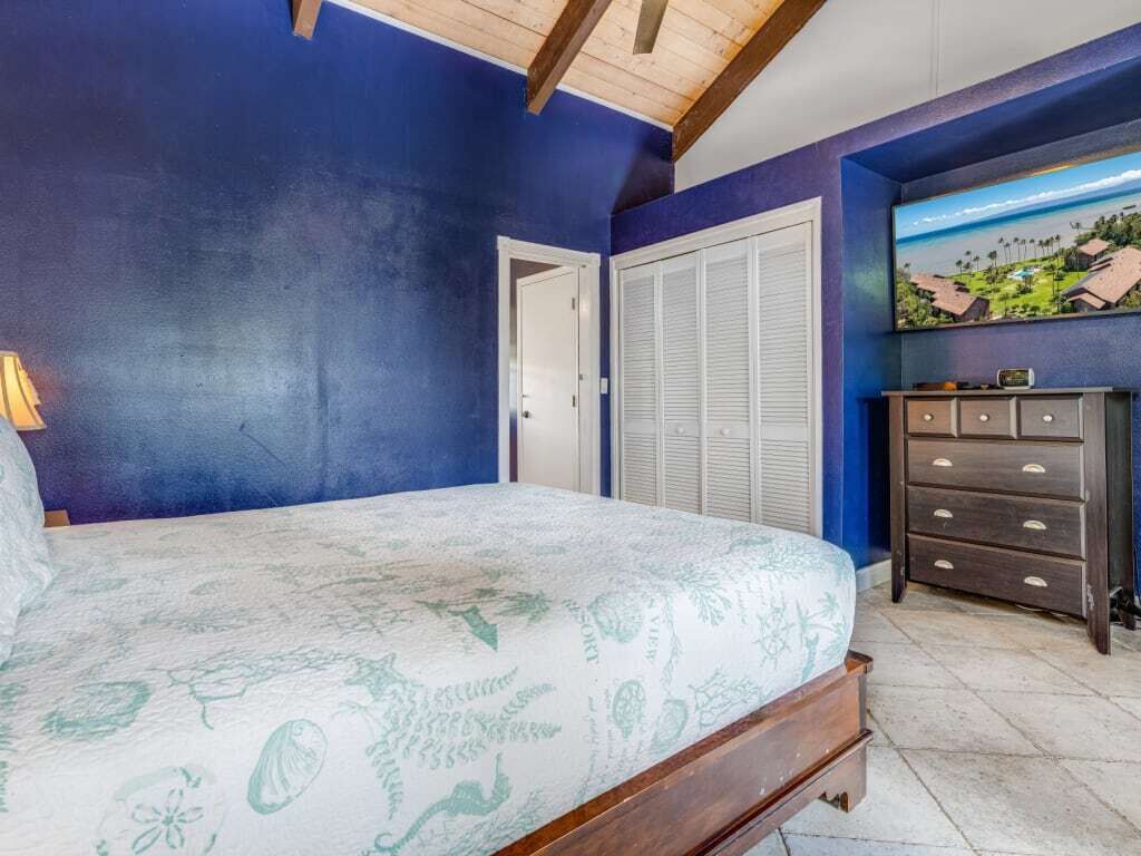 Une chambre à coucher avec un lit, une commode, une porte et un tableau accroché au mur.