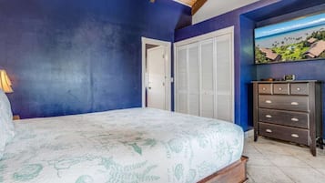 Une chambre à coucher avec un lit, une commode, une porte et un tableau accroché au mur.