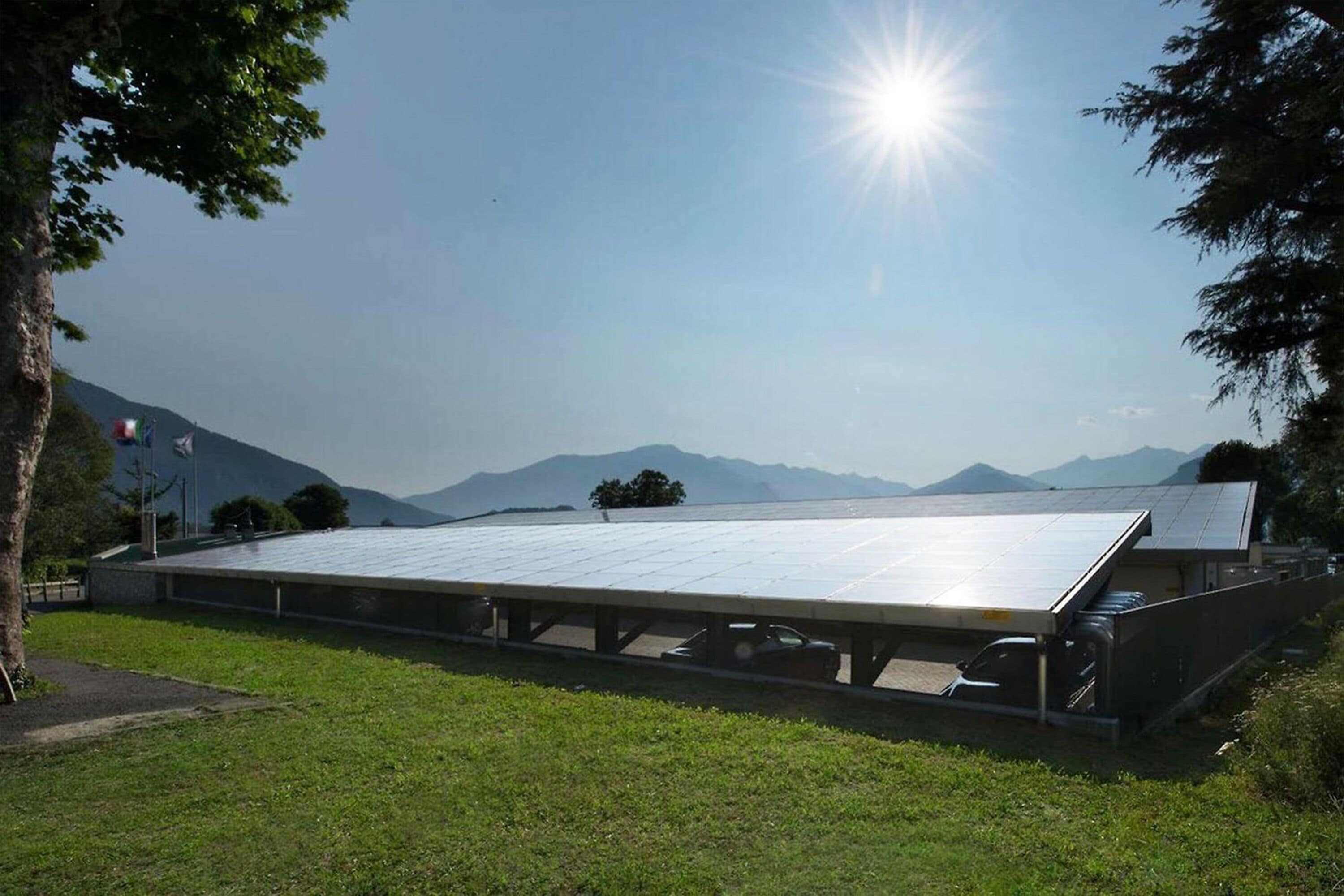 A building with a flat roof, surrounded by greenery and mountains in the background.