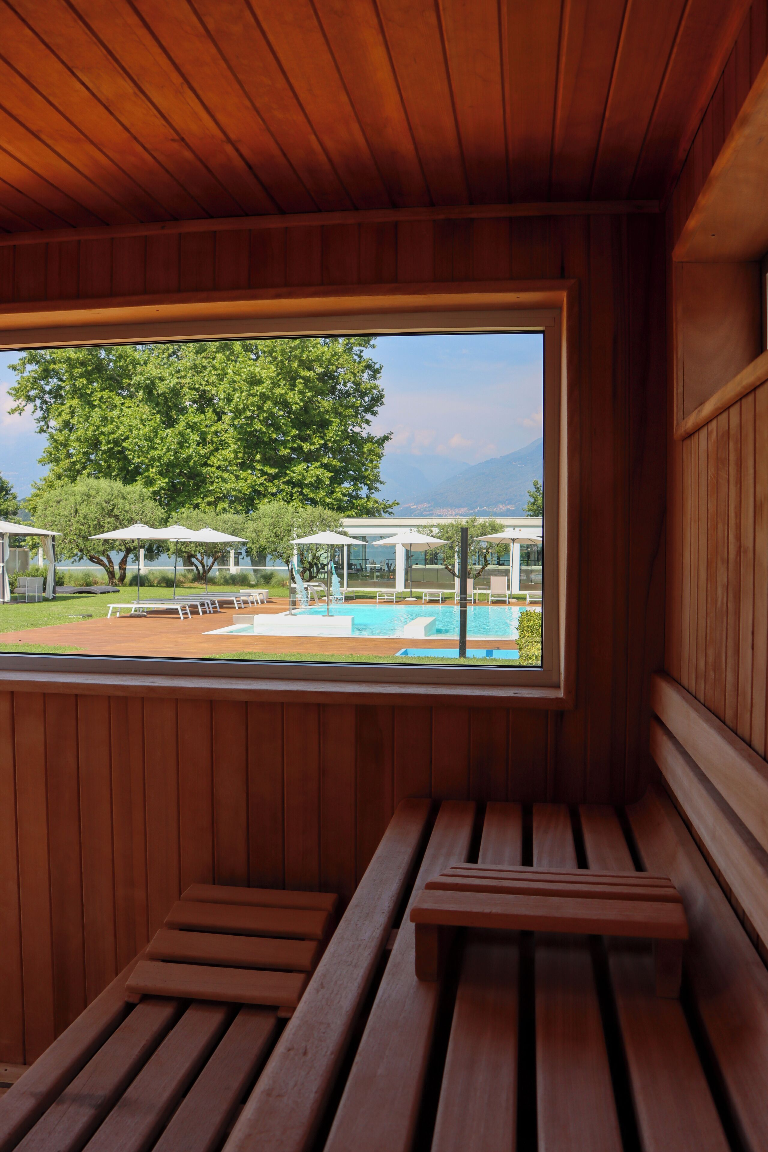 Un interno in legno con un'ampia finestra che si affaccia su una zona piscina.