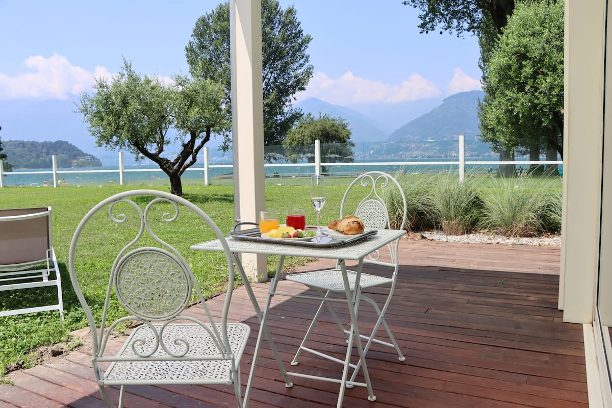 A patio with a table and chairs, overlooking a lake and mountains.