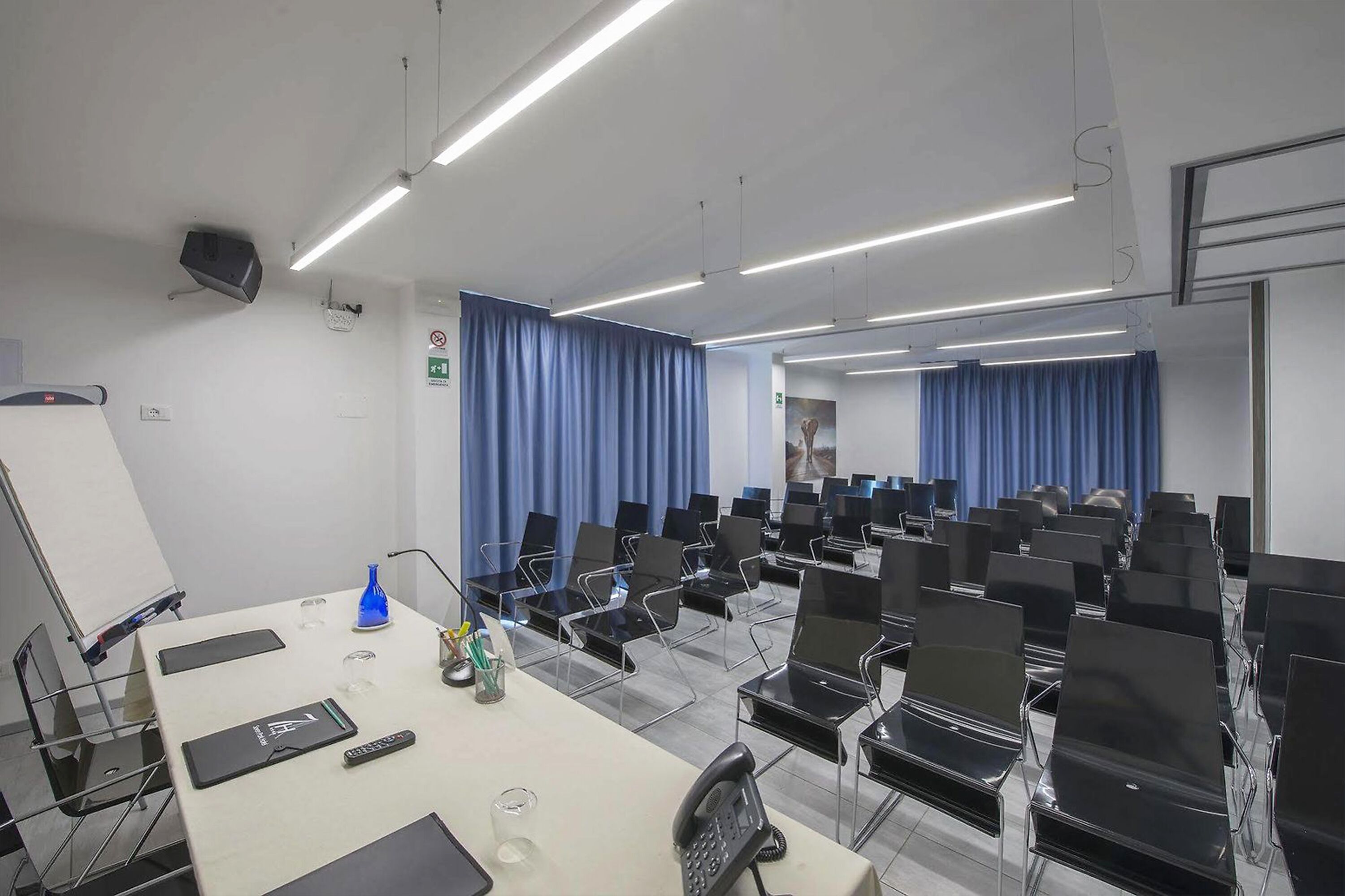A conference room with a long table, multiple chairs, a whiteboard, and a projector.