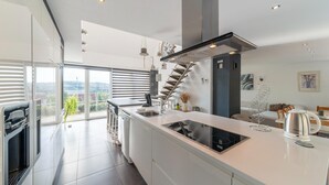 Een moderne keuken met een centraal eiland, een inbouwfornuis en uitzicht op de omgeving.