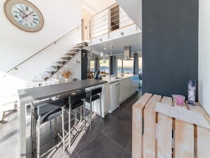 Une cuisine moderne dotée d’un îlot central, de tabourets de bar, d’un escalier et offrant une vue sur l’extérieur.