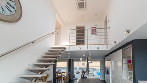 Een modern interieur met een trap, keuken, eetgedeelte en uitzicht naar buiten.