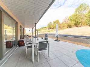 Une terrasse extérieure avec une table et des chaises, un espace abrité et une vue sur le paysage.