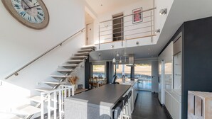 Een moderne keuken met een centraal eiland, een trap en uitzicht op de omgeving.