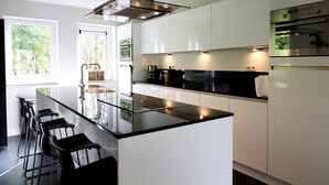 A modern kitchen with a central island, bar stools, and built-in appliances.