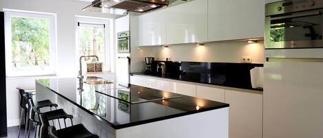 A modern kitchen with a central island, bar stools, and built-in appliances.