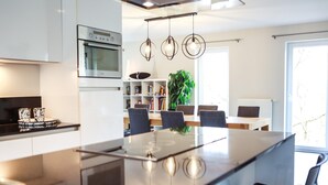 A modern kitchen with a central island, built-in oven, and pendant lighting.