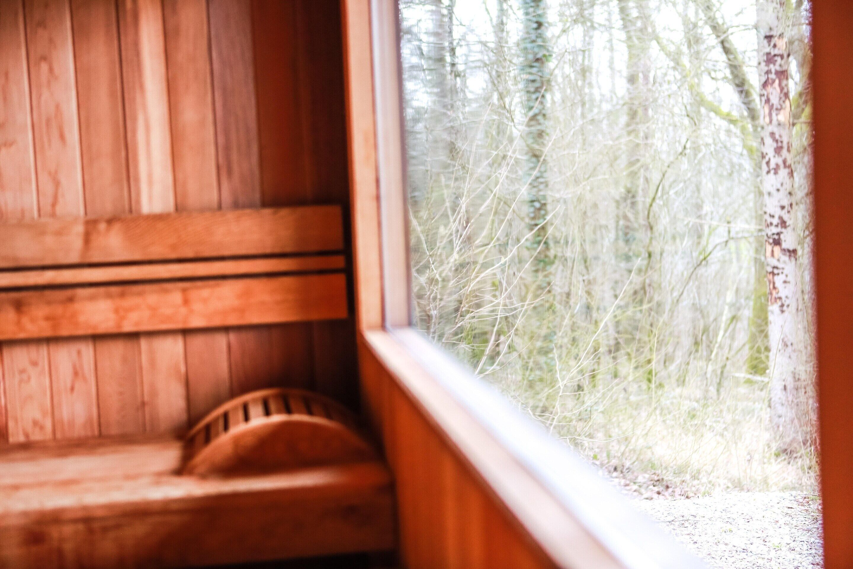 Un banco de madera junto a una ventana con vista a un bosque.