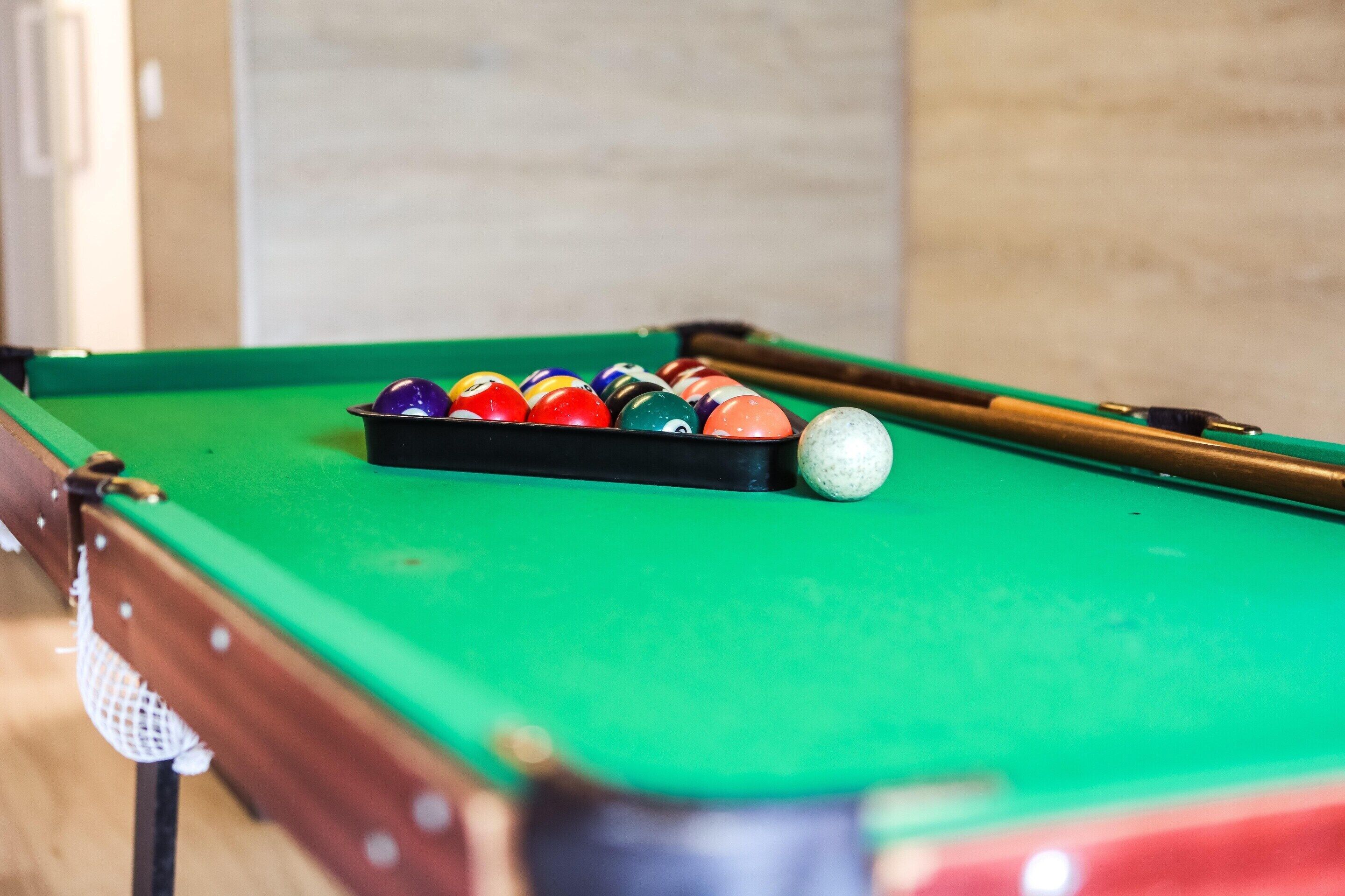 A pool table with a green felt surface and a set of billiard balls.