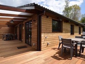 A wooden cabin with a deck, outdoor seating, and a covered area. - Renovated Chalet Near Durbuy (Durbuy)