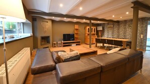 Ein modernes Wohnzimmer mit einer großen Eckcouch, einem Kamin, einem Fernseher und einer Wand mit ZEBRA-Muster.