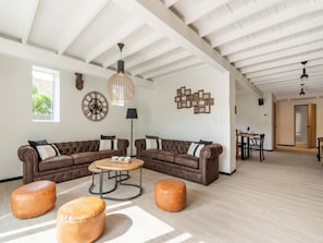 A spacious living area with a high ceiling, a large wooden ceiling, a brown leather sofa set, a round coffee table, and two leather ottomans. - Spacious Family Holiday Home (Mont-de-l'Enclus)