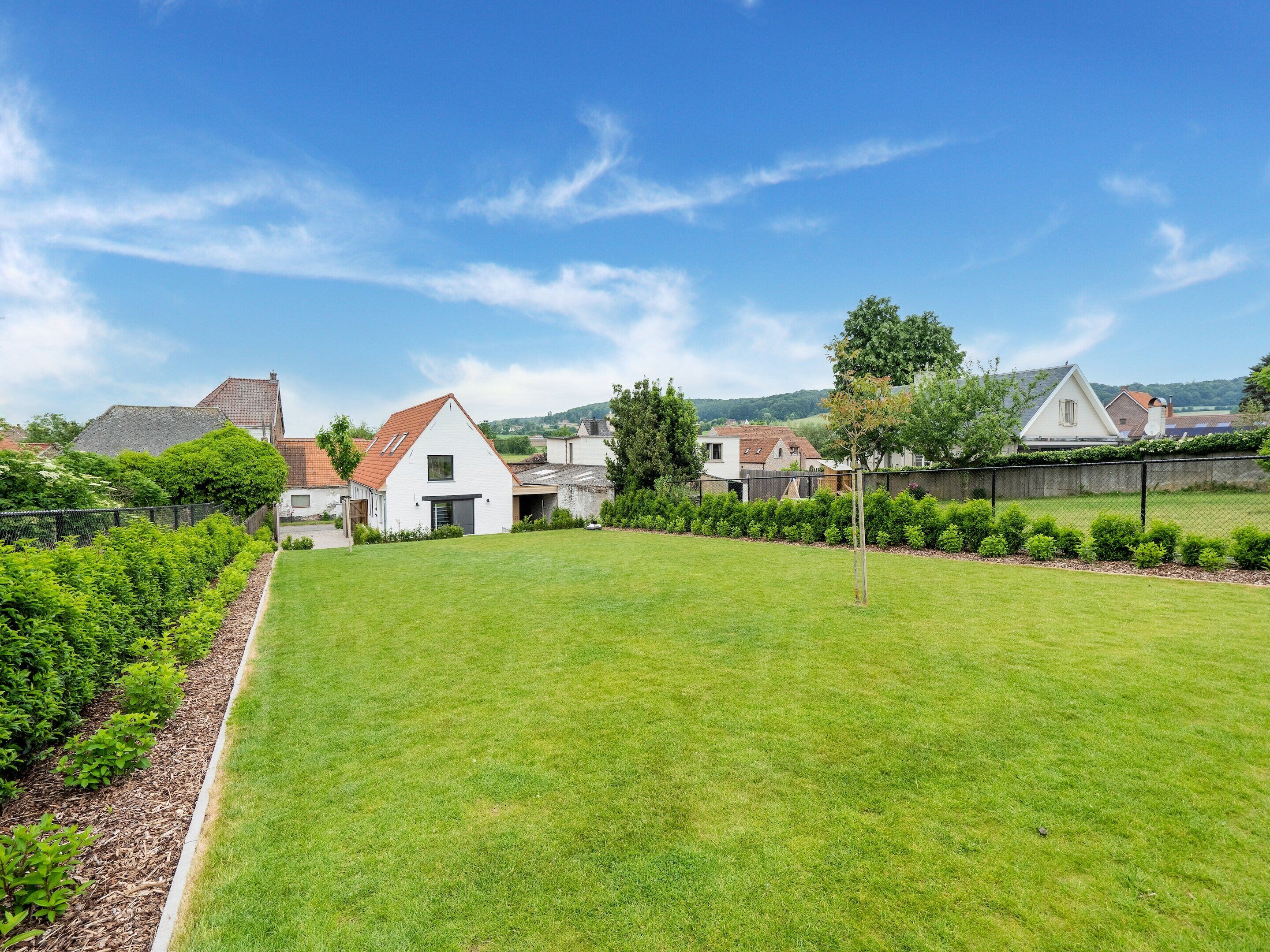 Een woonwijk met huizen, een verzorgd gazon en een heldere lucht.
