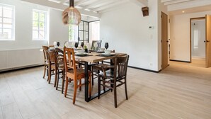A spacious dining area with a wooden table and chairs, a hanging pendant light, and large windows allowing natural light. - Spacious Family Holiday Home (Mont-de-l'Enclus)
