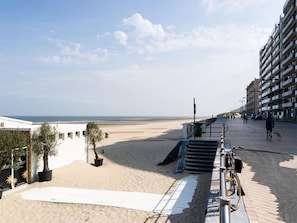 A beachside promenade with a sandy path leading to the beach, a staircase, and a building with balconies. - Middelkerke Mobile Home With Garden (Middelkerke)